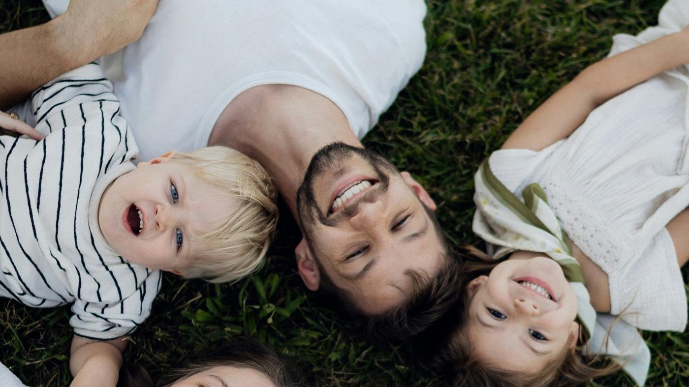 Family lying together on grass, representing the people life insurance protects